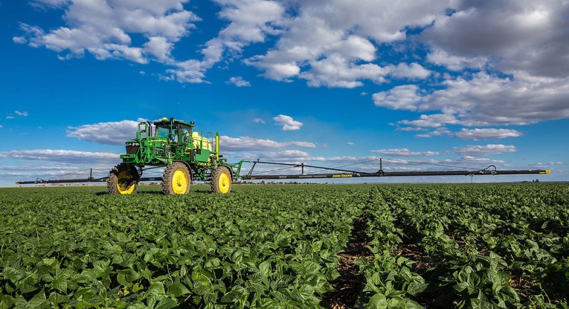 John Deere M4030 self-propelled sprayer applying crop protection in a South African field as it drives toward the camera — built for precision and performance.