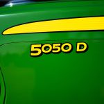 A photo of a close-up of the front nose of a John Deere 5050D tractor showing the tractor name with the John Deere green