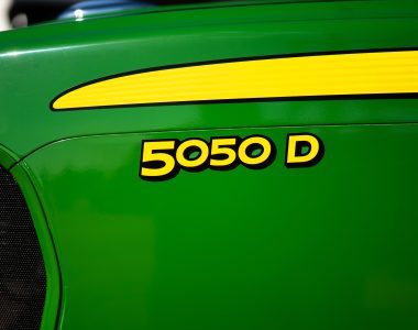 A photo of a close-up of the front nose of a John Deere 5050D tractor showing the tractor name with the John Deere green