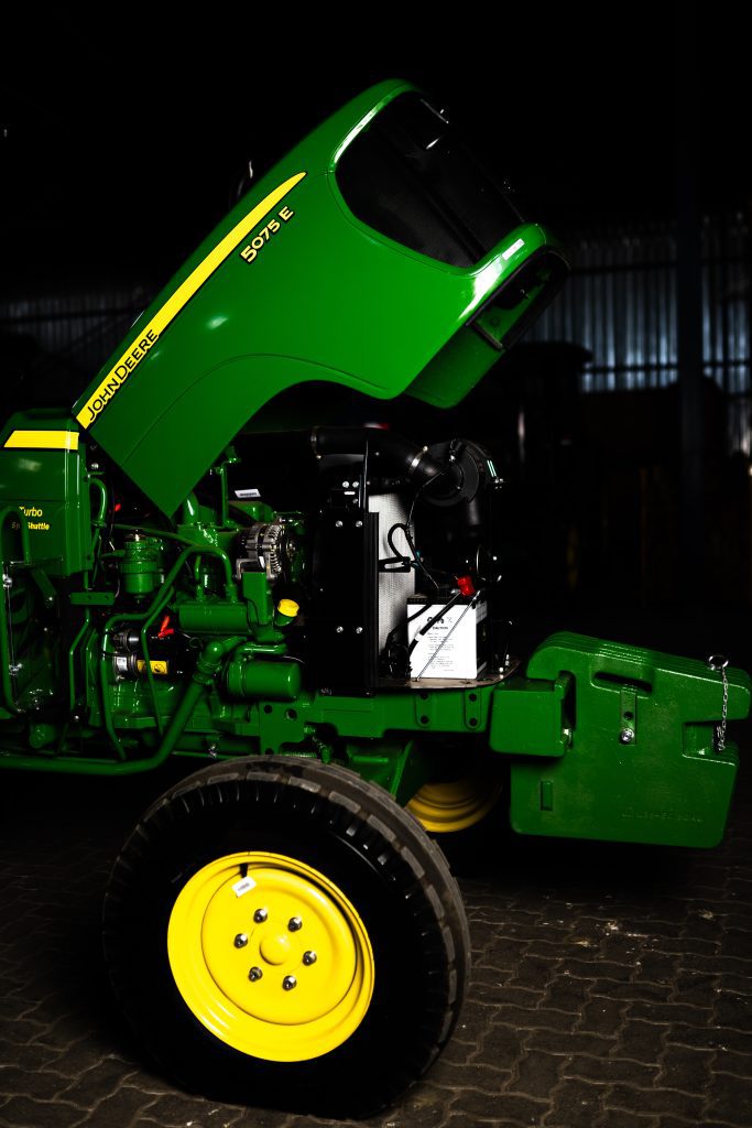 A photo of the engine and open hood of a John Deere 5055E tractor.