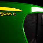 A photo of a close-up of the front nose of a John Deere 5055E tractor showing the tractor name with the John Deere green
