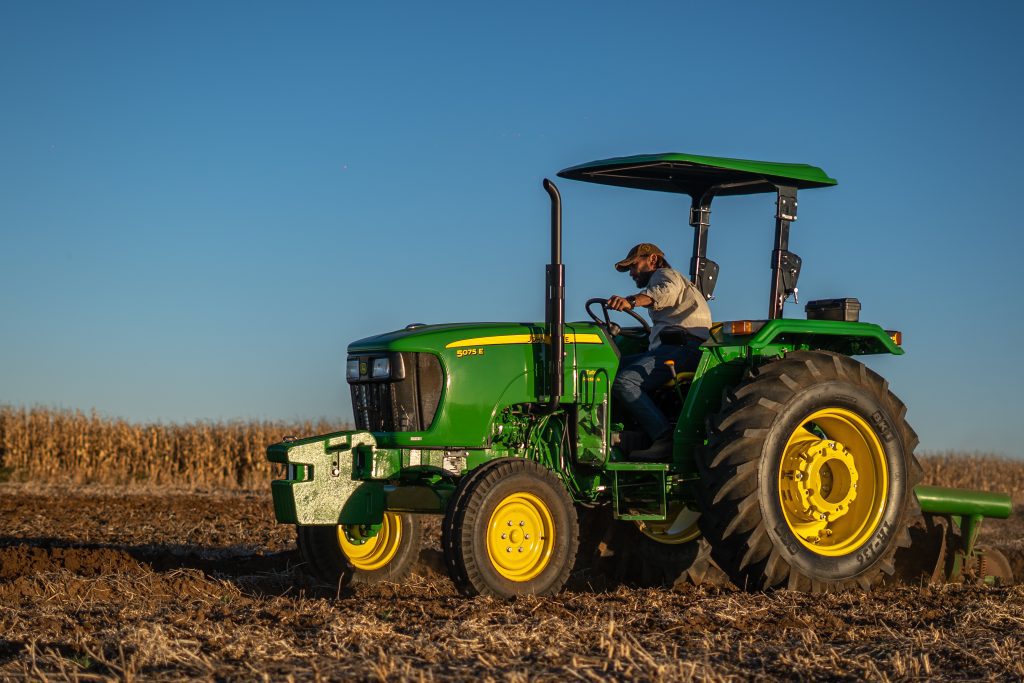 A photo of a John Deere 5075E tractor working in the field.