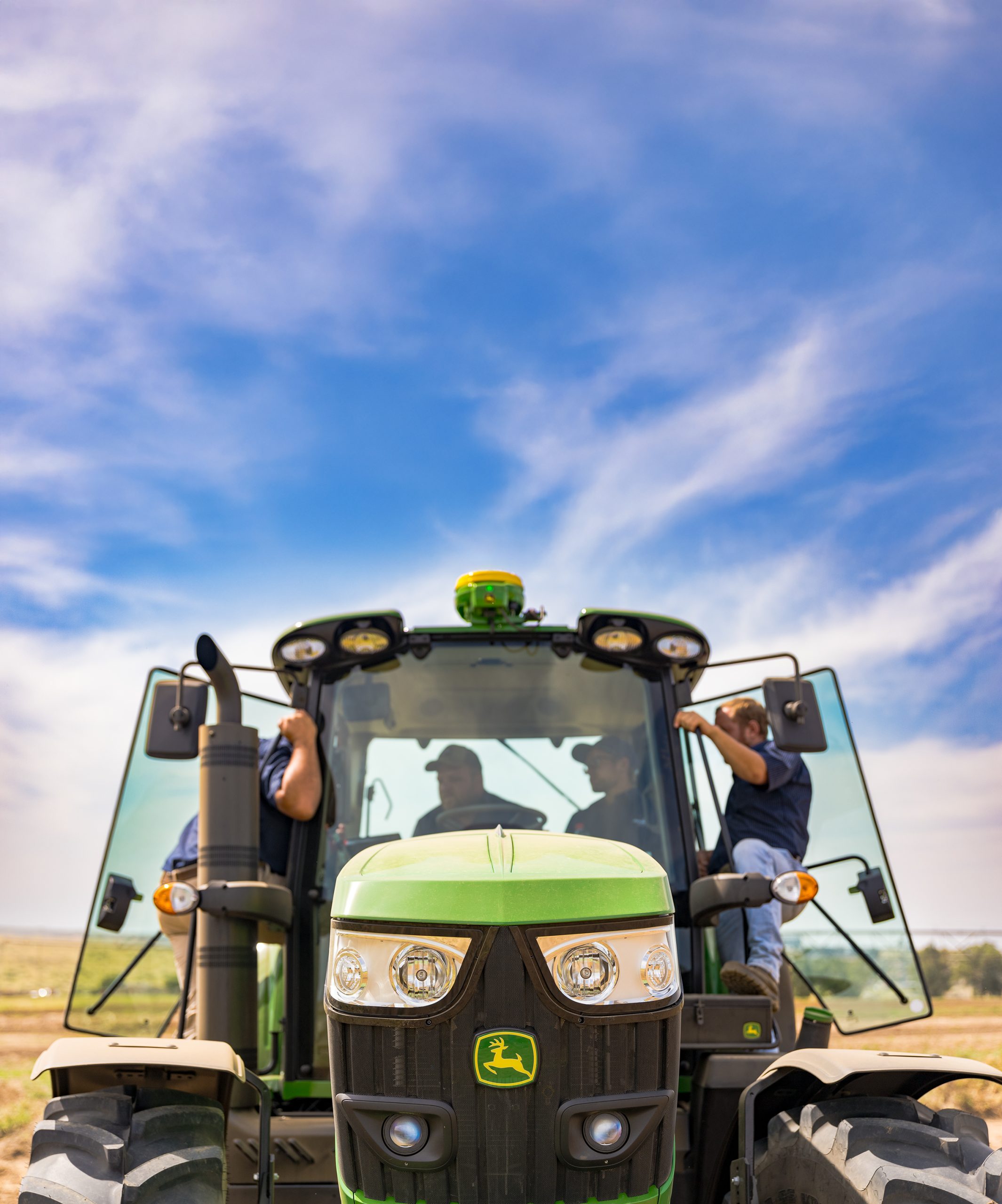 Technicians with John Deere Tractor A photo of the fornt of a John Deere tractor, badge clearly visible and apprentice technicians in the cab