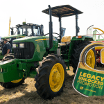 John Deere 5075E tractor standing in a South African field with the Legacy Unlocked Promotion cutout standing next to it.
