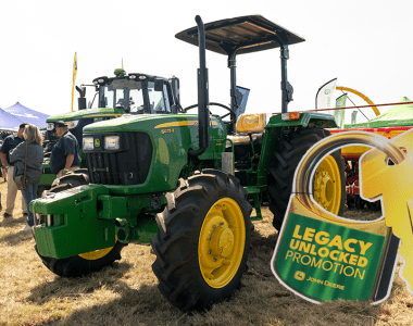 John Deere 5075E tractor standing in a South African field with the Legacy Unlocked Promotion cutout standing next to it.