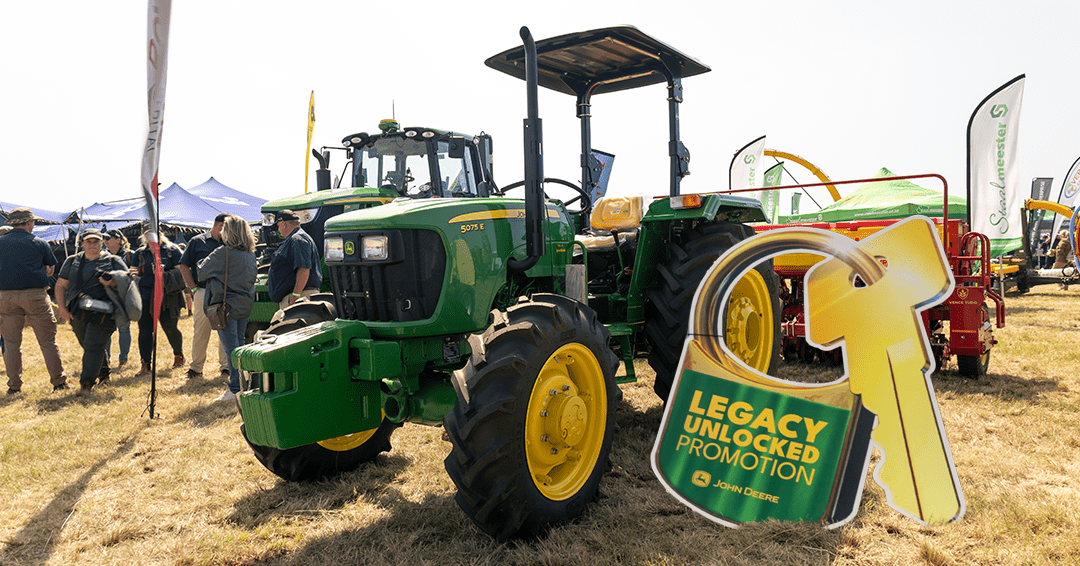 John Deere 5075E tractor standing in a South African field with the Legacy Unlocked Promotion cutout standing next to it.
