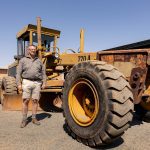 Photo of the old John Deere 770A Motor Grader with a representative of Elite Guys