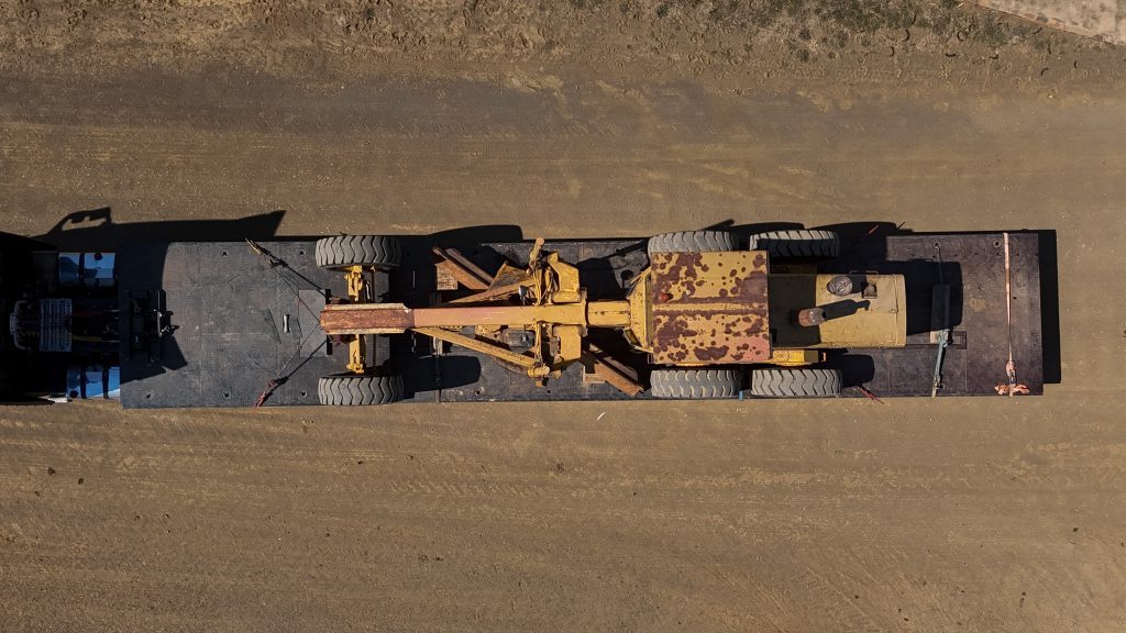 Top view of the old John Deere 770A Motor Grader on back of loading truck.