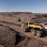 A John Deere 460 P-Tier Articulated dump truck transporting material across challenging mining terrain.