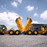 Two John Deere 460 P-Tier ADTs back-to-back with their buckets lifted. The Yellow Iron makes a nice contrast against the blue sky.