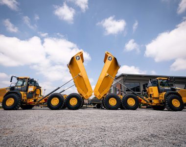 Two John Deere 460 P-Tier ADTs back-to-back with their buckets lifted. The Yellow Iron makes a nice contrast against the blue sky.