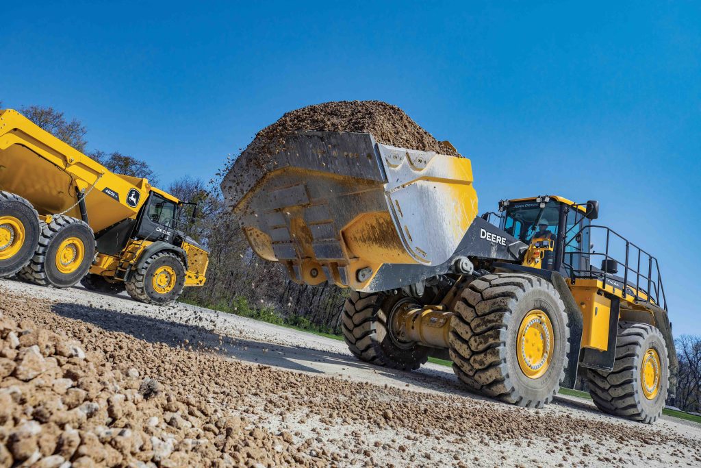 John Deere construction equipment working in a quarry, moving and loading aggregate material in a demanding mining environment.