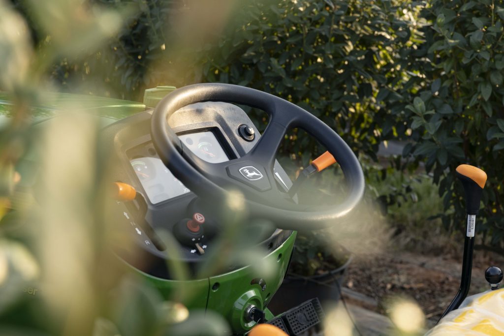 John Deere 3036EN compact tractor in an orchard, showing the steering column and some control levers
